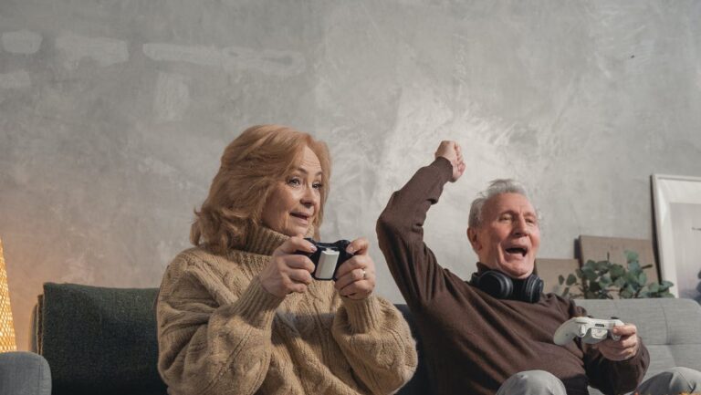 elderly couple sitting on couch playing video games