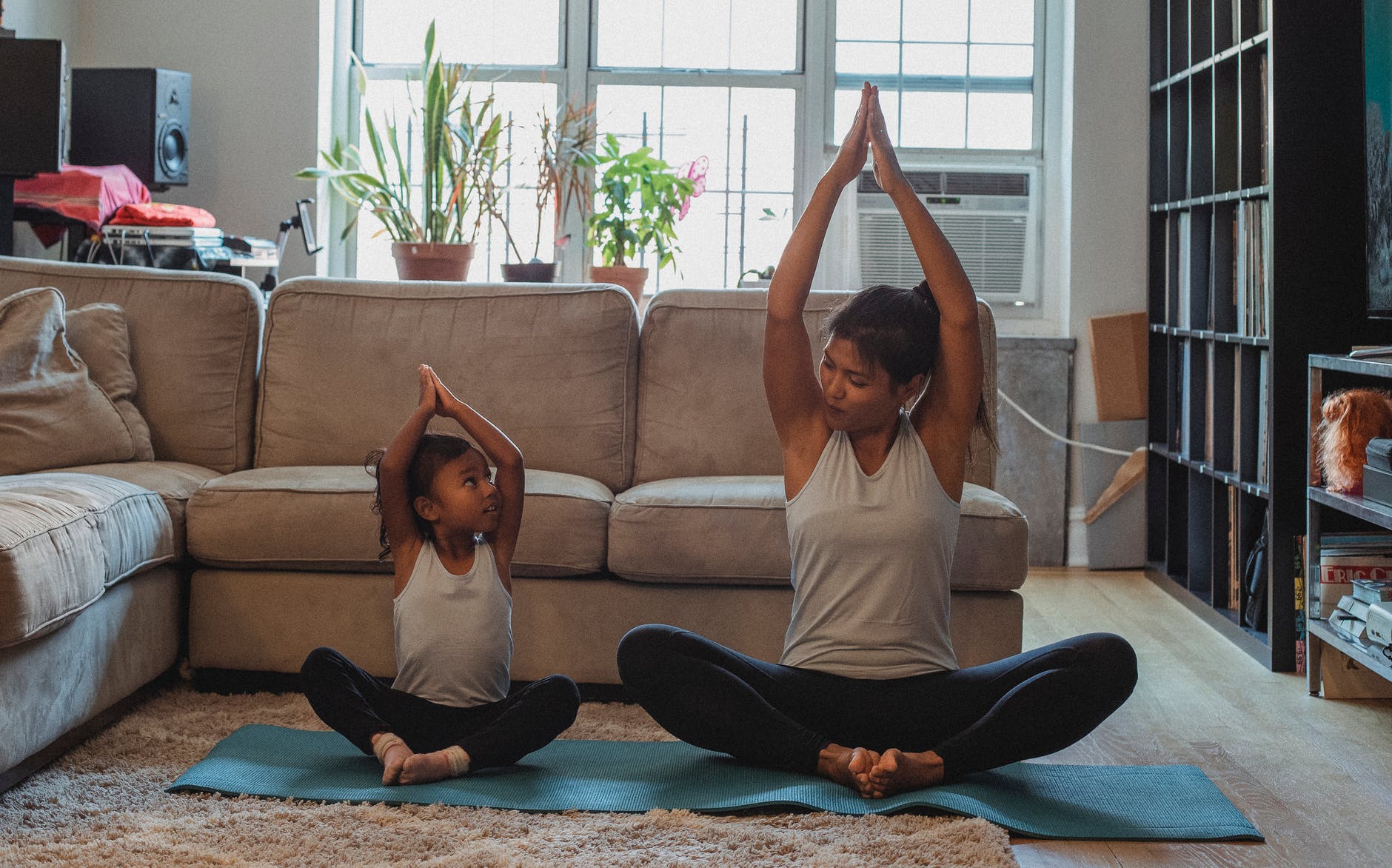 positive asian mother and daughter practicing yoga together at home